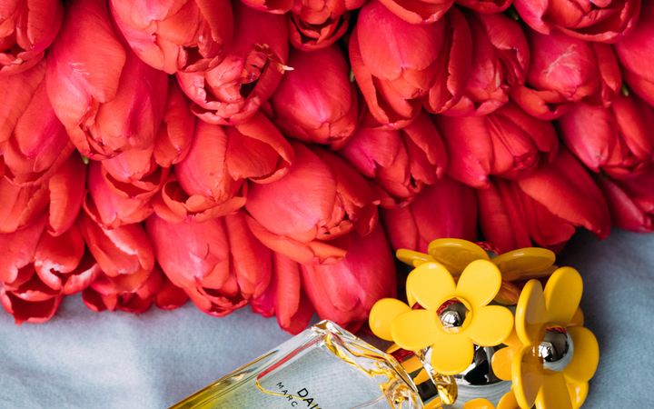Elegant perfume bottle with red tulips on a soft background, radiating fragrance and beauty.