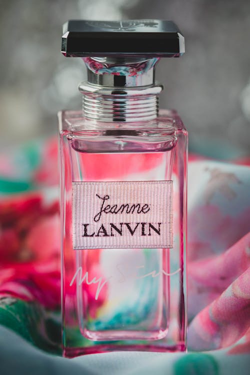 Transparent perfume bottle on vibrant fabric