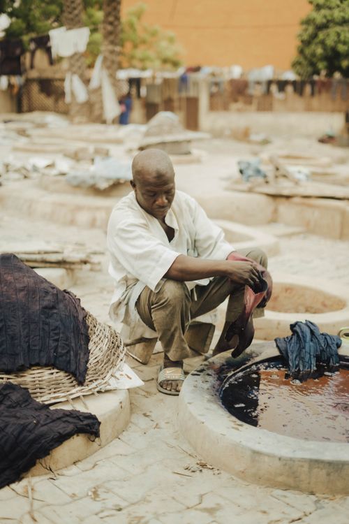 Free Man engaged in traditional fabric dyeing outdoors, showcasing cultural craftsmanship. Stock Photo