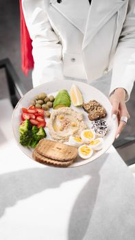 A colorful Mediterranean breakfast with hummus, eggs, vegetables, and bread served in Kerman, Iran.