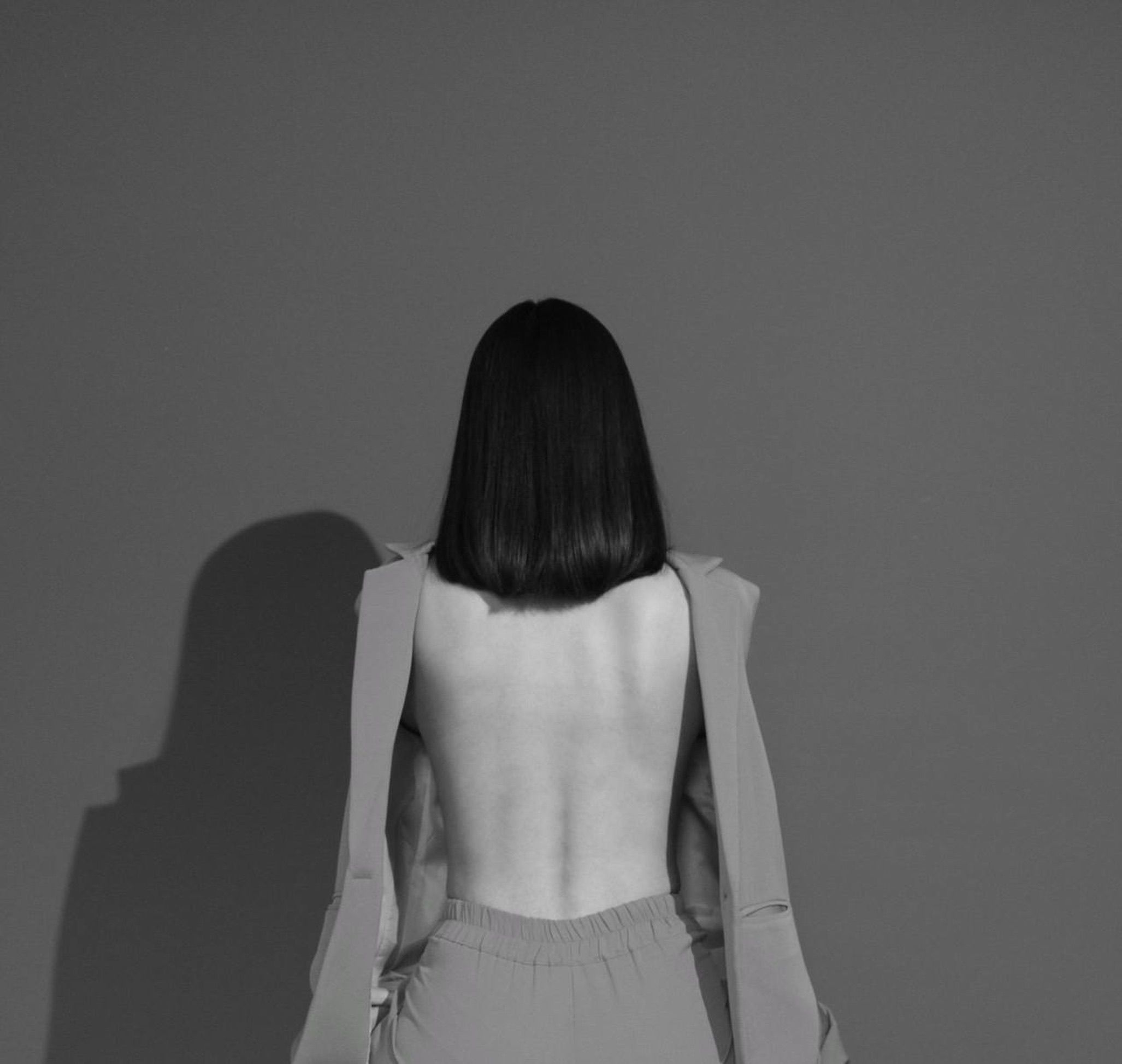 Elegant monochrome fashion portrait featuring a backless design and shadow play.