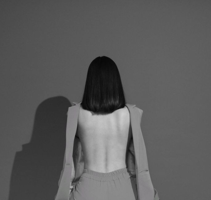 Elegant monochrome fashion portrait featuring a backless design and shadow play.