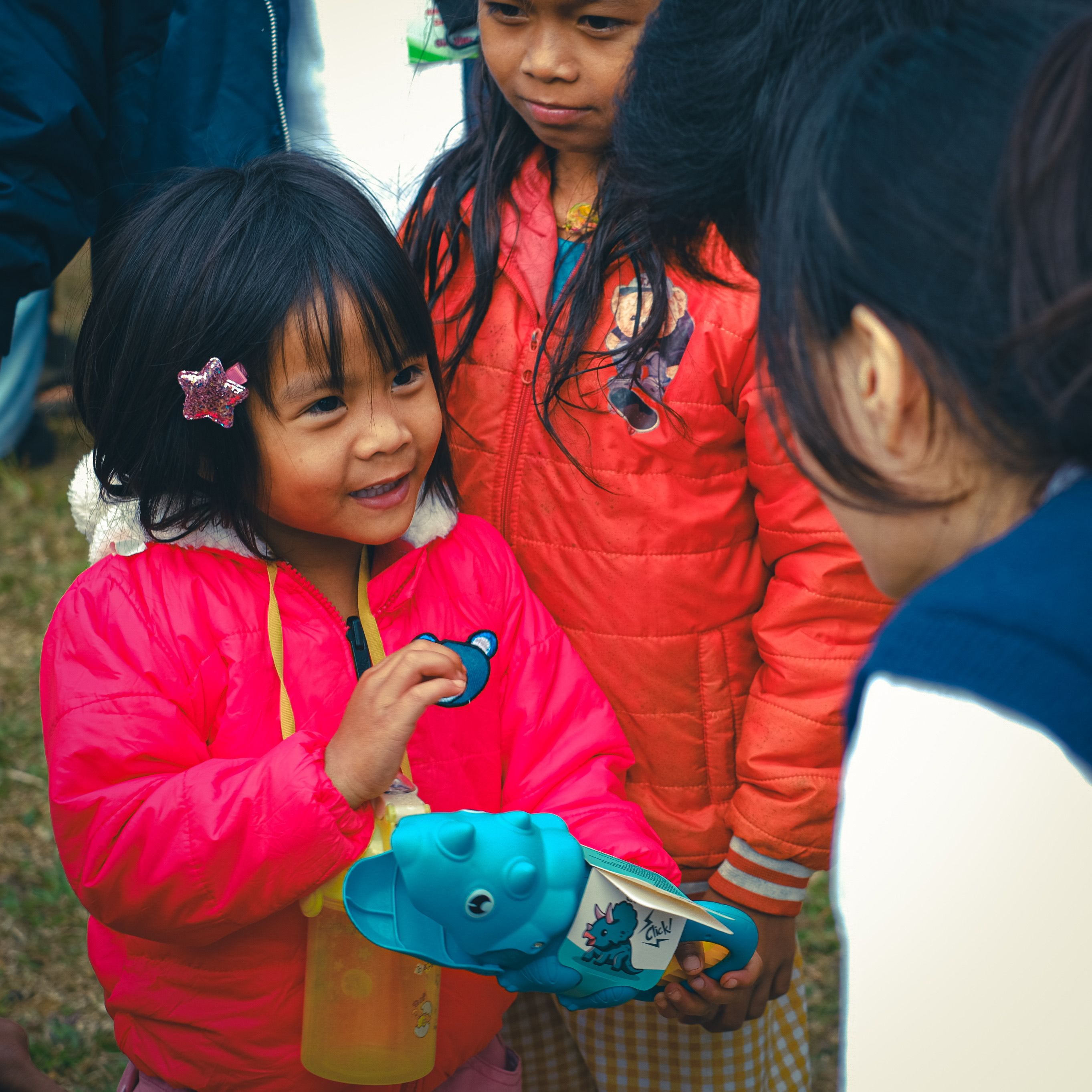 Girl in Red Jacket Holding Blue Toy