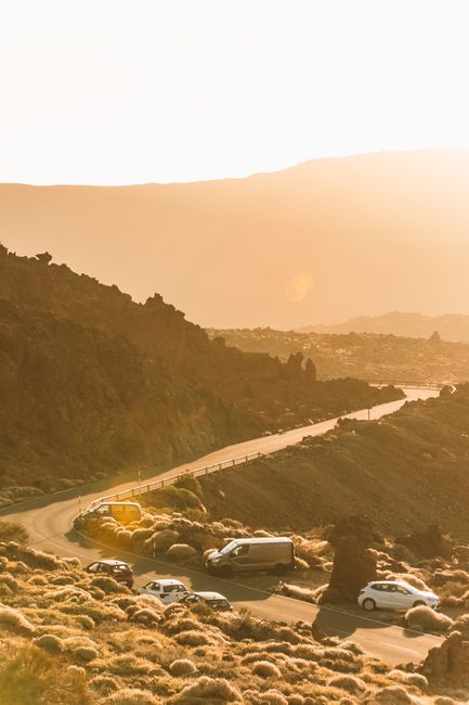 Captivating sunset view of vehicles on a winding desert road, emphasizing travel and adventure.