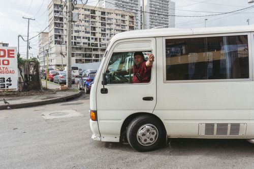 Free City view with a driver in a white van on bustling streets of Cidade do Panamá. Stock Photo