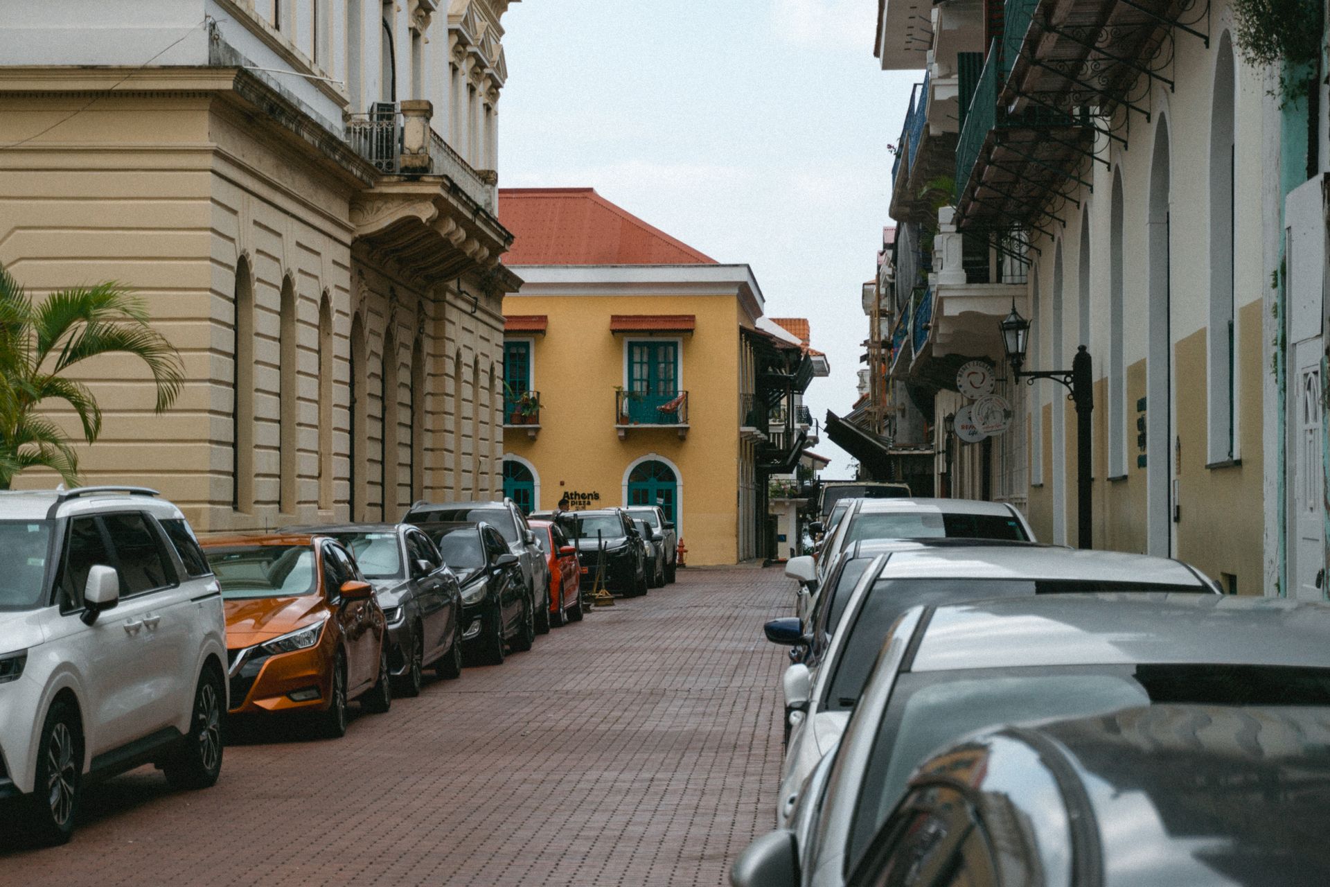 Charming street in Panama City with parked cars and colonial architecture under a clear sky.