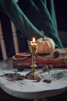 A vintage candle illuminates a rustic table, surrounded by pumpkins and autumn accents.