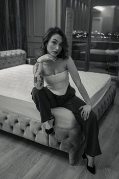 Elegant woman seated on a bed in a stylish, modern bedroom.