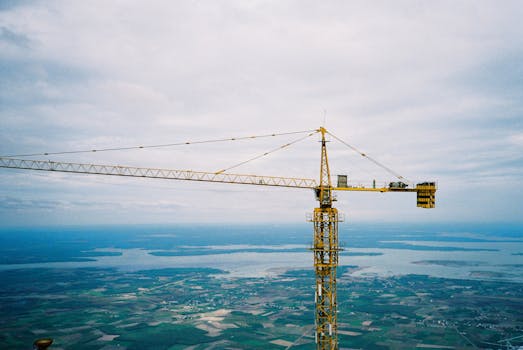 High crane towering over vast landscape, capturing industrial progress.