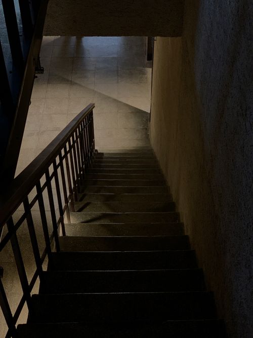 Free A moody, dimly lit staircase casting dramatic shadows on the walls. Stock Photo