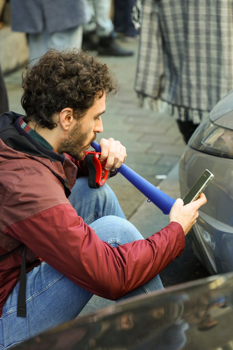 A Man Sitting With A Smartphone