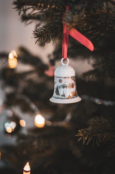 Close-up of a decorated bell with festive lights on a Christmas tree.