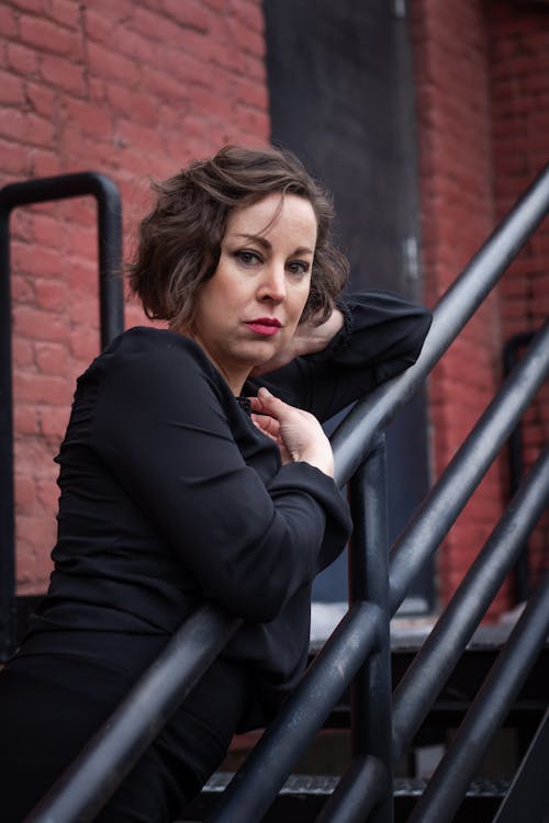 Brunette Woman in Black Blouse Posing by Railing