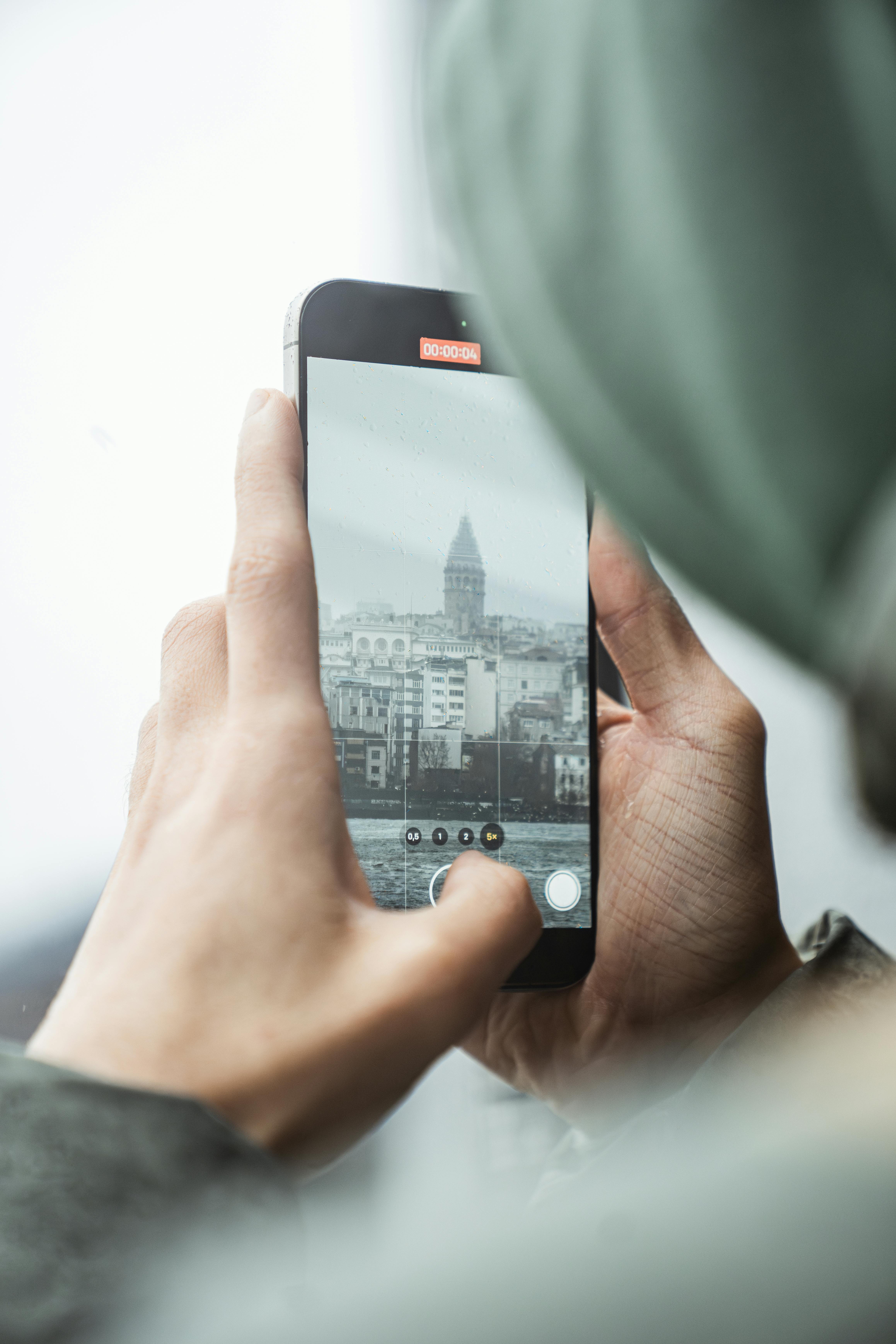 A person photographs the iconic Galata Tower in Istanbul using a smartphone, showcasing modern technology.