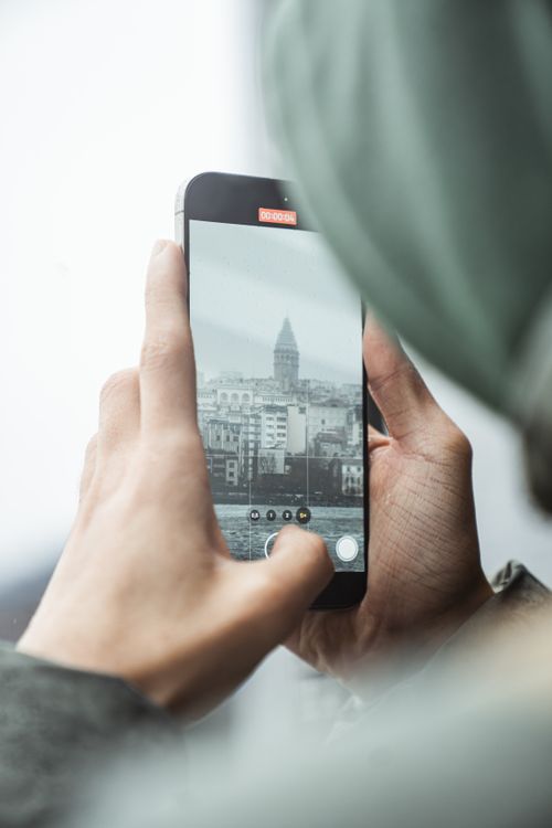 Free A person photographs the iconic Galata Tower in Istanbul using a smartphone, showcasing modern technology. Stock Photo