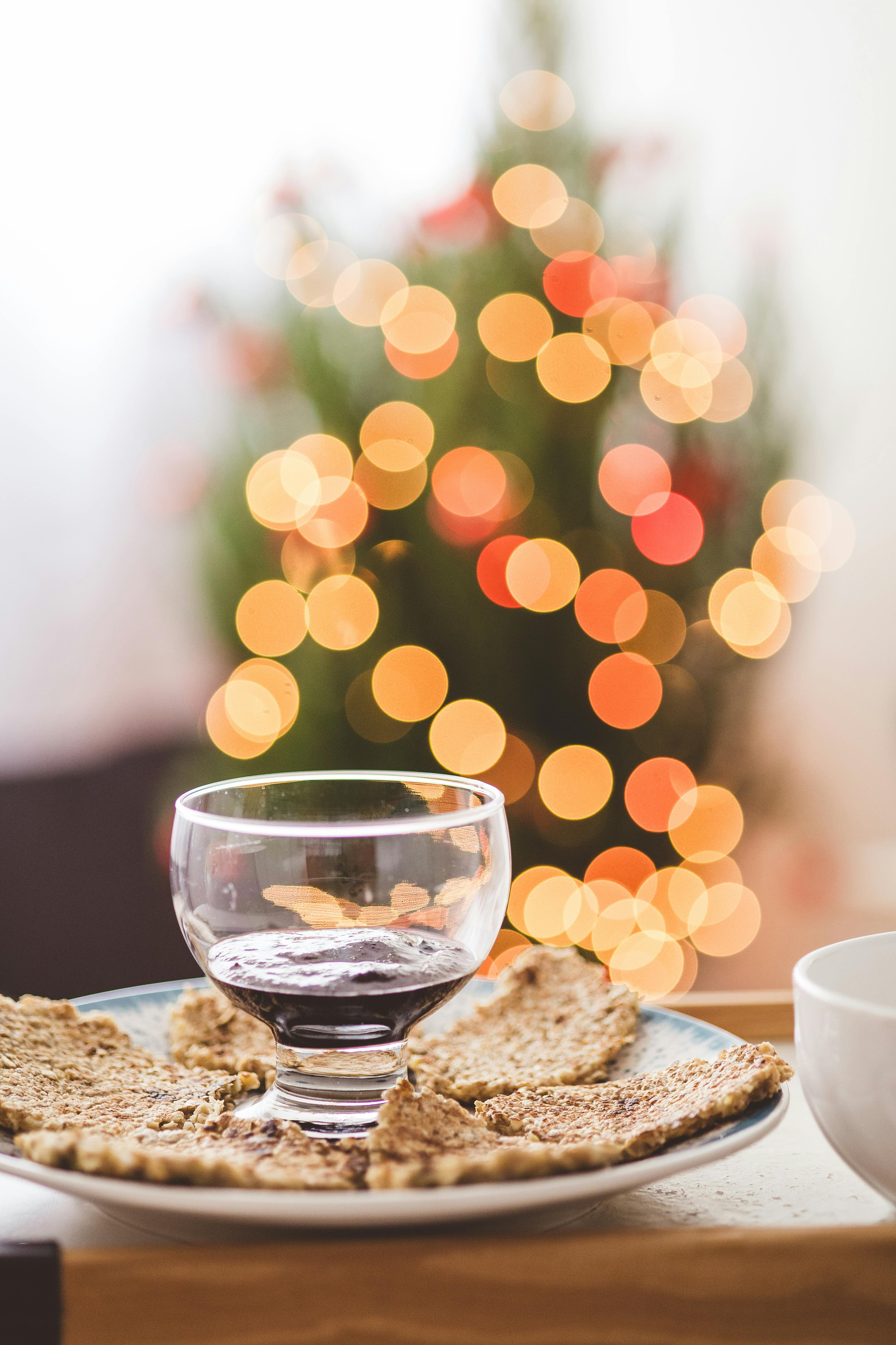 A cozy Christmas scene with wine, cookies, and bokeh lights.