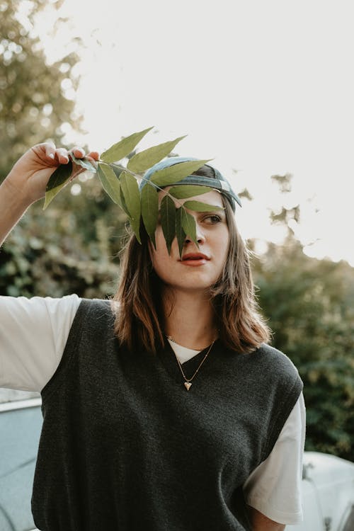 Young Woman Covering Her Face with Leaves