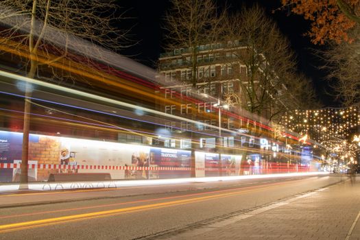 Dynamic night view of Hamburg city streets with festive lights and motion blur from passing vehicles.