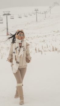 Stylish woman in winter clothing walking through snowy slopes of Kayseri, enjoying a cold day outdoors.