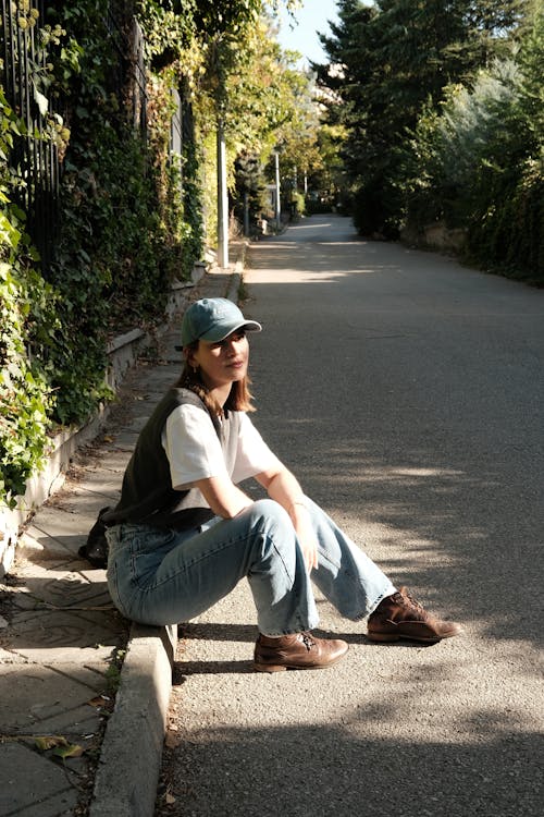 Young Woman Sitting on a Curb in Sunlight 