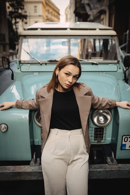 Model in a Light Brown Blazer and Gray Pants Leans Against an Off-road Vehicle