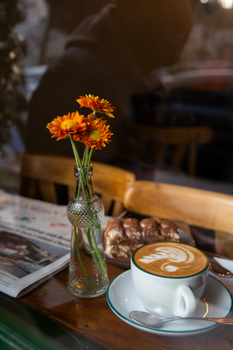 Warm café atmosphere with a coffee cup, flowers, and cake in Amman, Jordan.