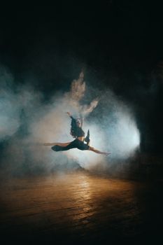 A dancer leaps gracefully on a smoky stage, capturing the essence of movement and artistry.