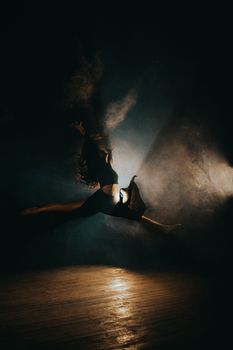 High-energy dance leap captured with dramatic backlighting and atmospheric smoke effects.