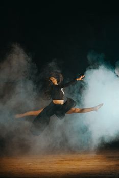 A dancer in a dramatic leap with smoke creating silhouettes and shadows.
