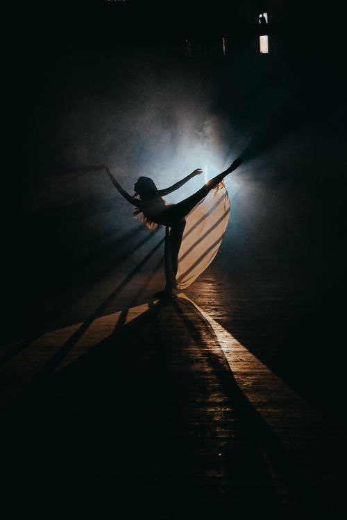 Free Silhouette of a dancer performing gracefully with dramatic backlighting creating striking shadows. Stock Photo