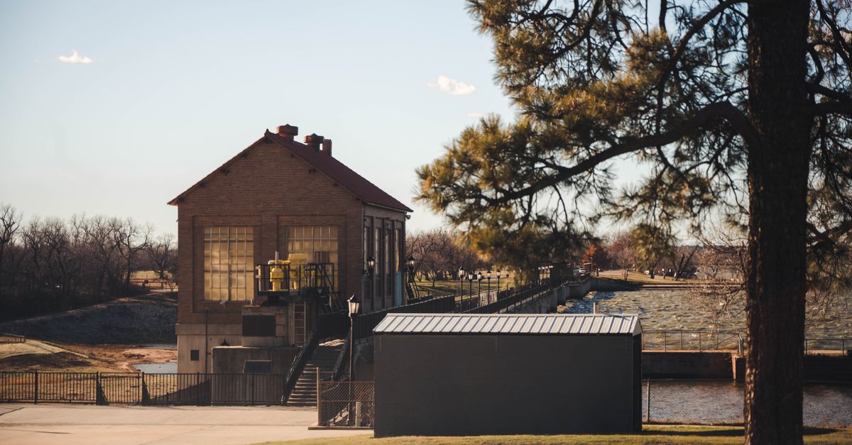 Charming view of a historic building near Lake Overholser Dam, Oklahoma City, with clear skies and lush greenery.