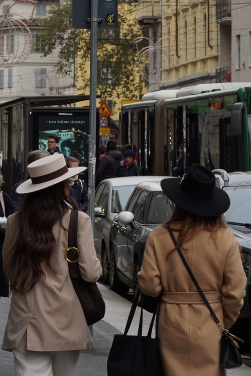 Free Two women in stylish hats walking on a busy city street with traffic and pedestrians. Stock Photo