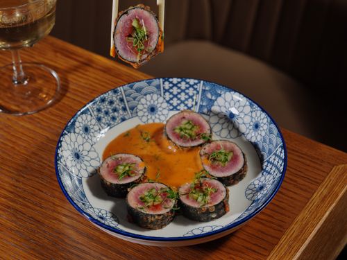 Free Exquisite sushi rolls served on a traditional patterned plate, perfect for a fine dining experience. Stock Photo