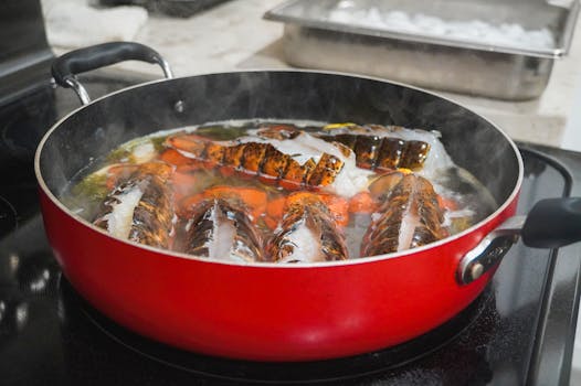 Fresh lobster tails being cooked in a red pot, emitting steam, on a stovetop.