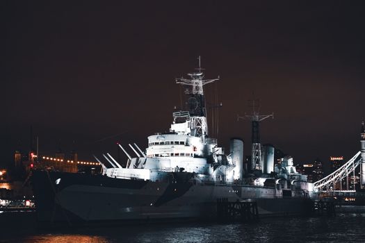 A stunning night view of HMS Belfast illuminated on the River Thames in London, United Kingdom.