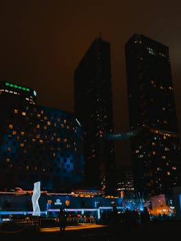 A dramatic view of modern skyscrapers illuminated at night, showcasing urban architecture.