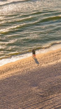 A couple enjoying a romantic walk on a sandy beach with waves in the background.