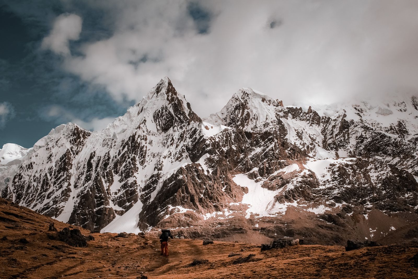 Snow-covered Andean peaks above a lone hiker in Peru's Cusco region