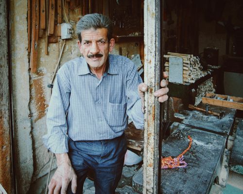 Free Elderly man with mustache standing in rural workshop, inviting and nostalgic. Stock Photo