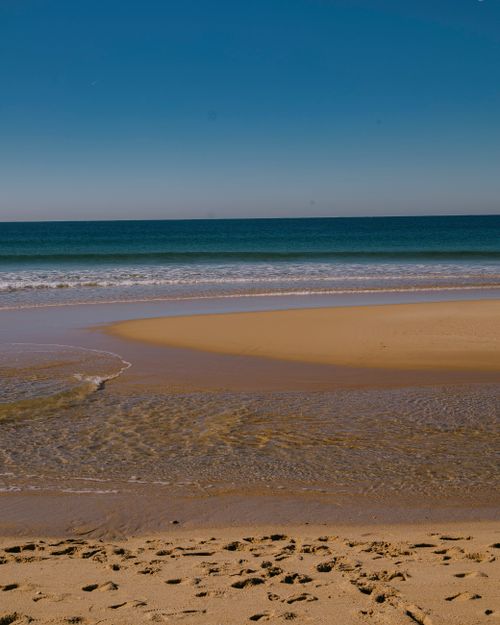 Free A tranquil beach scene with golden sand and turquoise sea under a clear blue sky. Stock Photo
