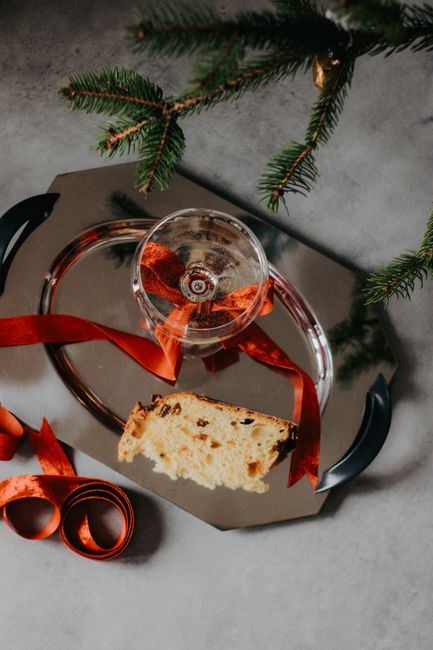 Elegant Christmas setup with panettone, ribbon, and glass on a festive tray.