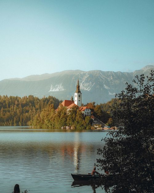 Free Bled Island with the Church of the Assumption, surrounded by Lake Bled and scenic mountains at sunset. Stock Photo