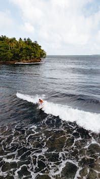 Aerial view of surfer catching waves near Pilar, Philippines. Perfect for adventure and travel visuals.