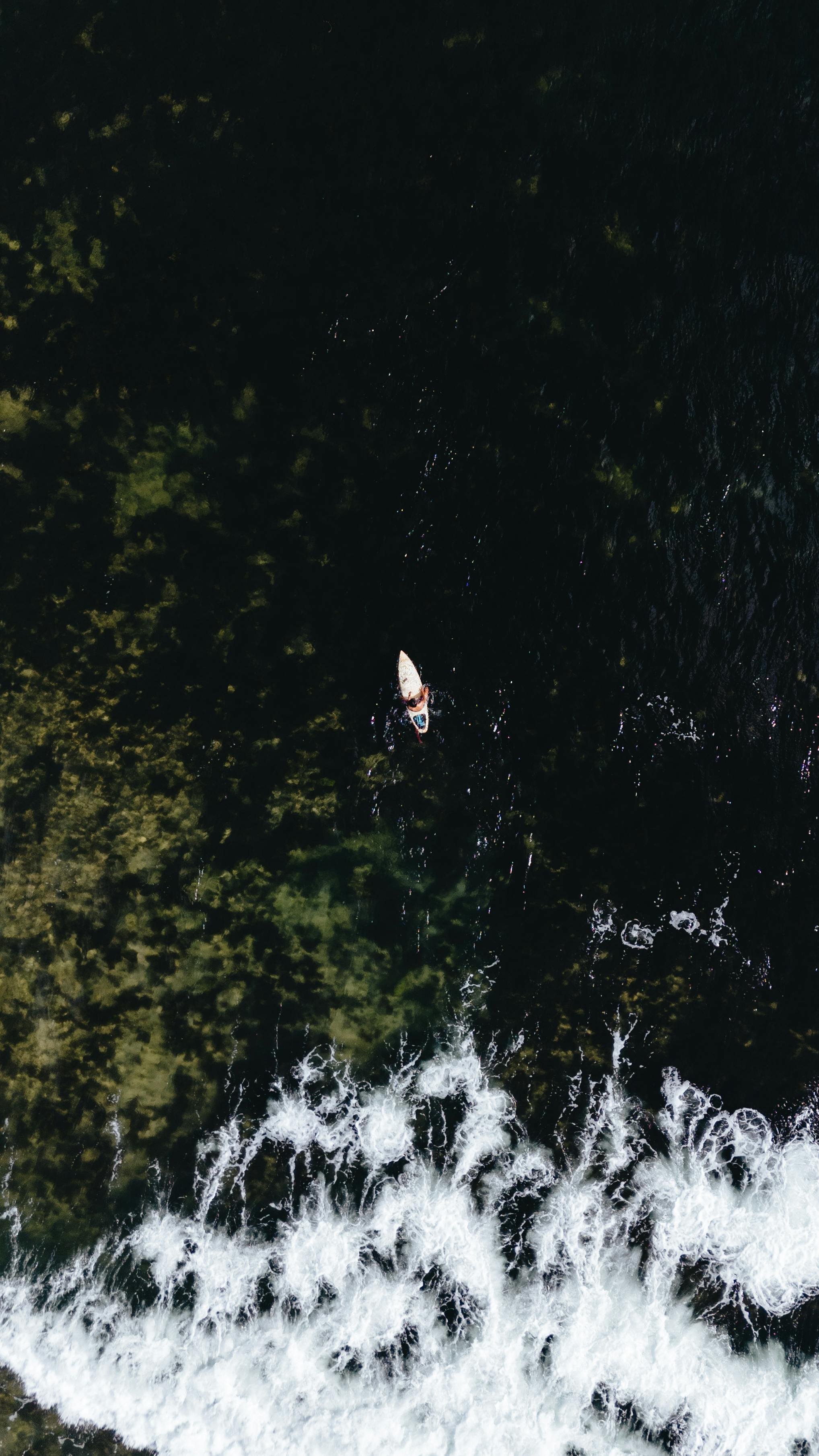 Drone shot of a canoe on the sea near the coast with visible waves, taken in Pilar, Philippines.