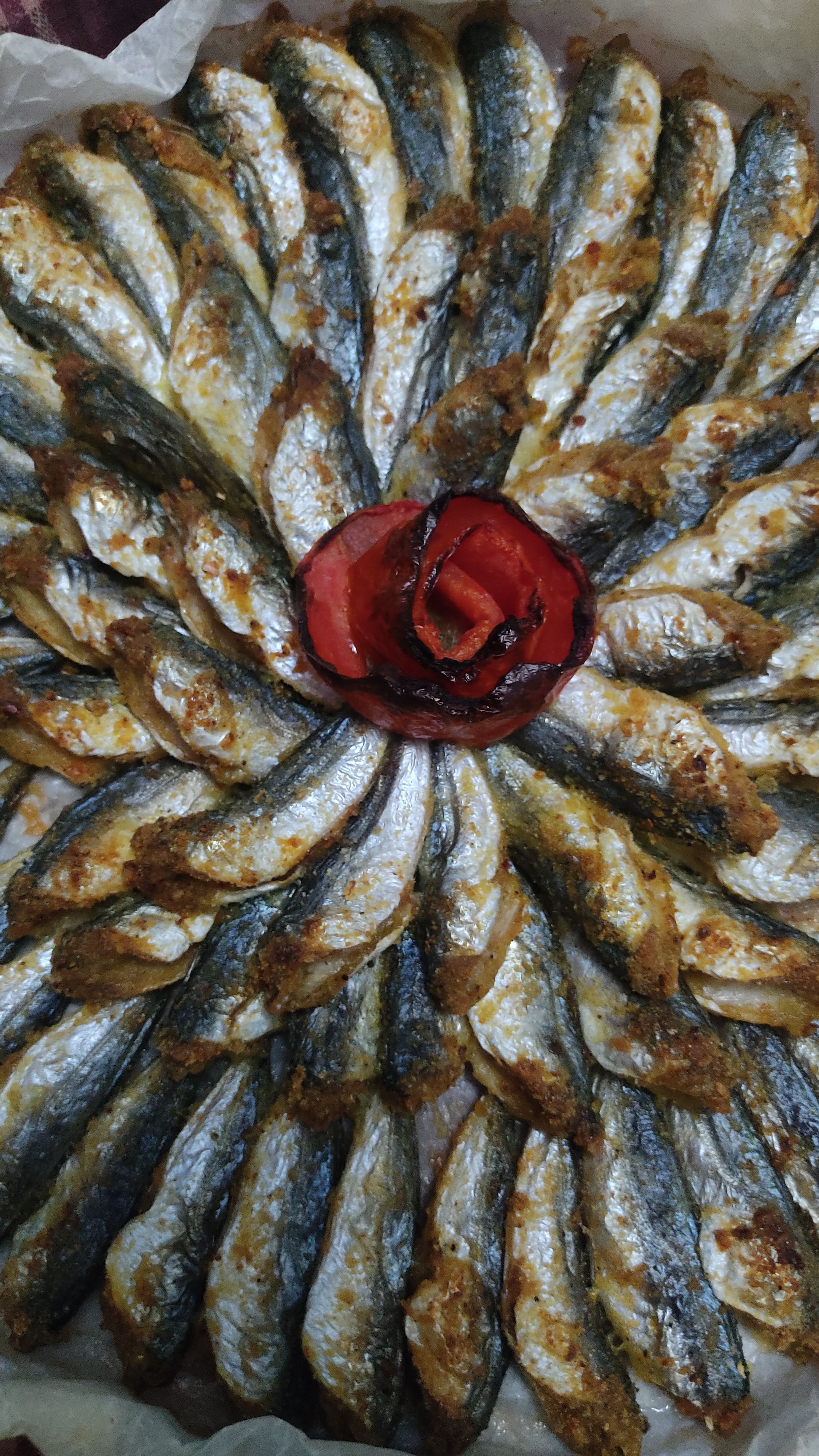 A close-up of a beautifully arranged baked anchovy dish with roasted red pepper garnish in Istanbul, Turkey.