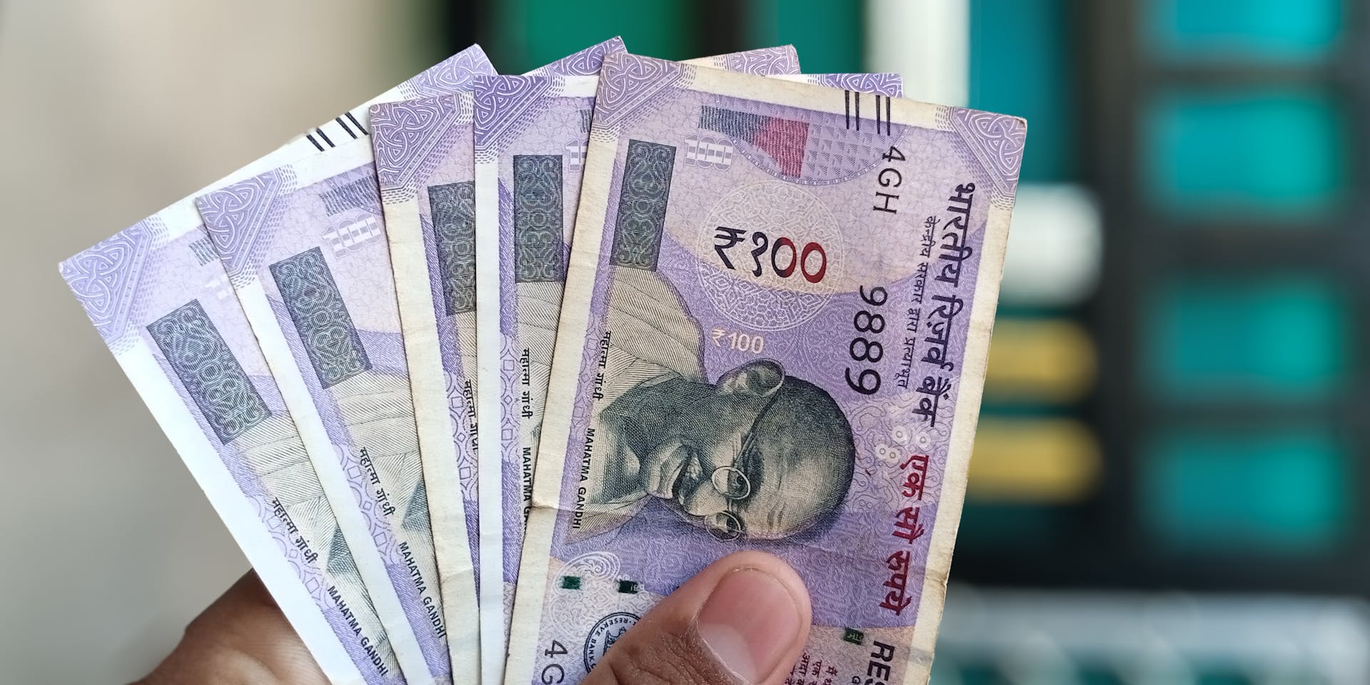 Close-up view of holding Indian 100 rupee banknotes, showcasing currency details and design.