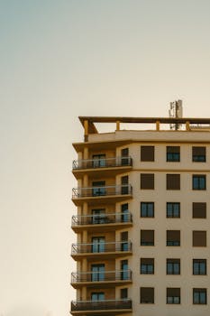 A modern residential building with multiple balconies seen at sunset.