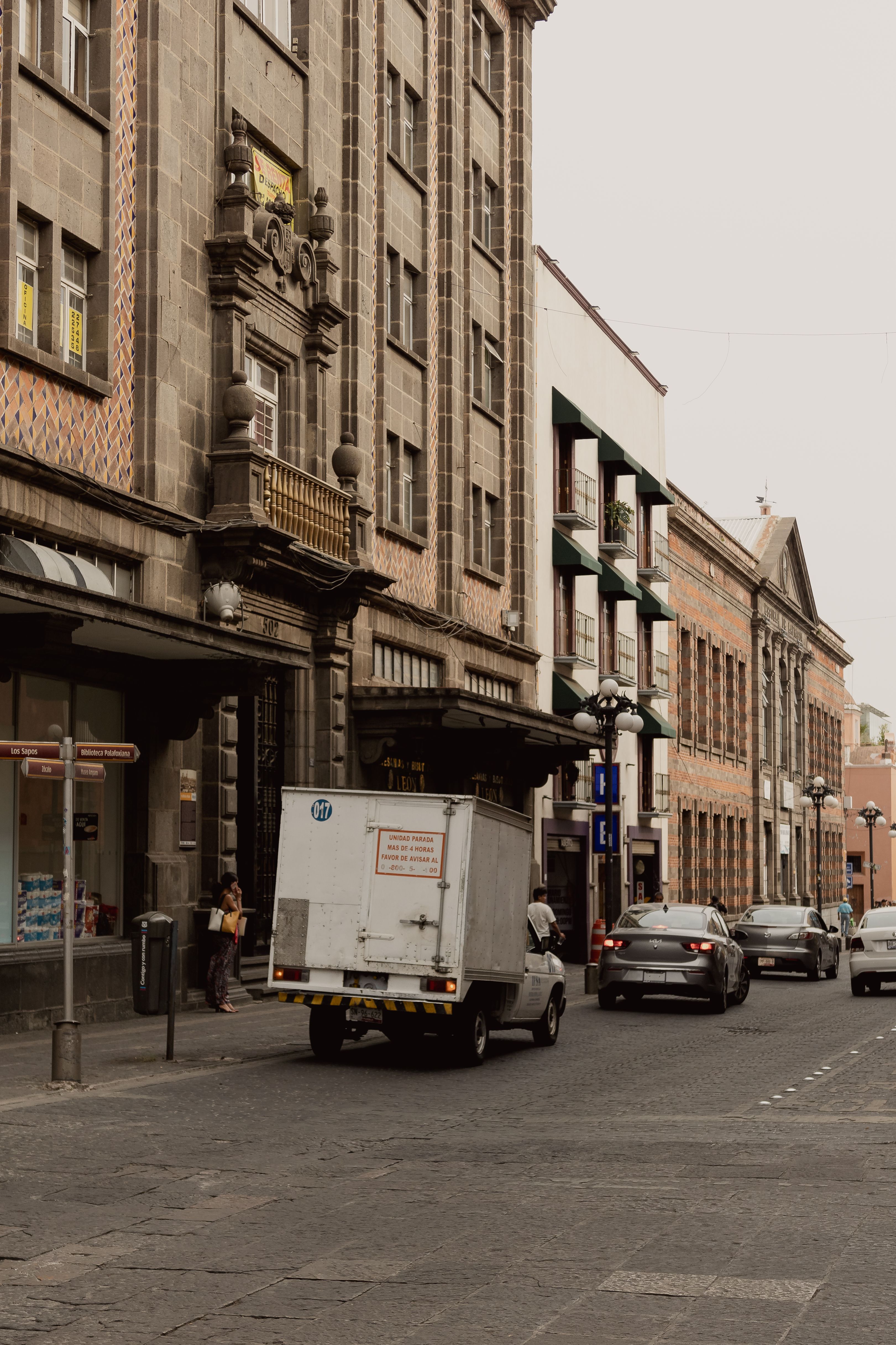 Street view of historic buildings and vehicles in Puebla's city center.
