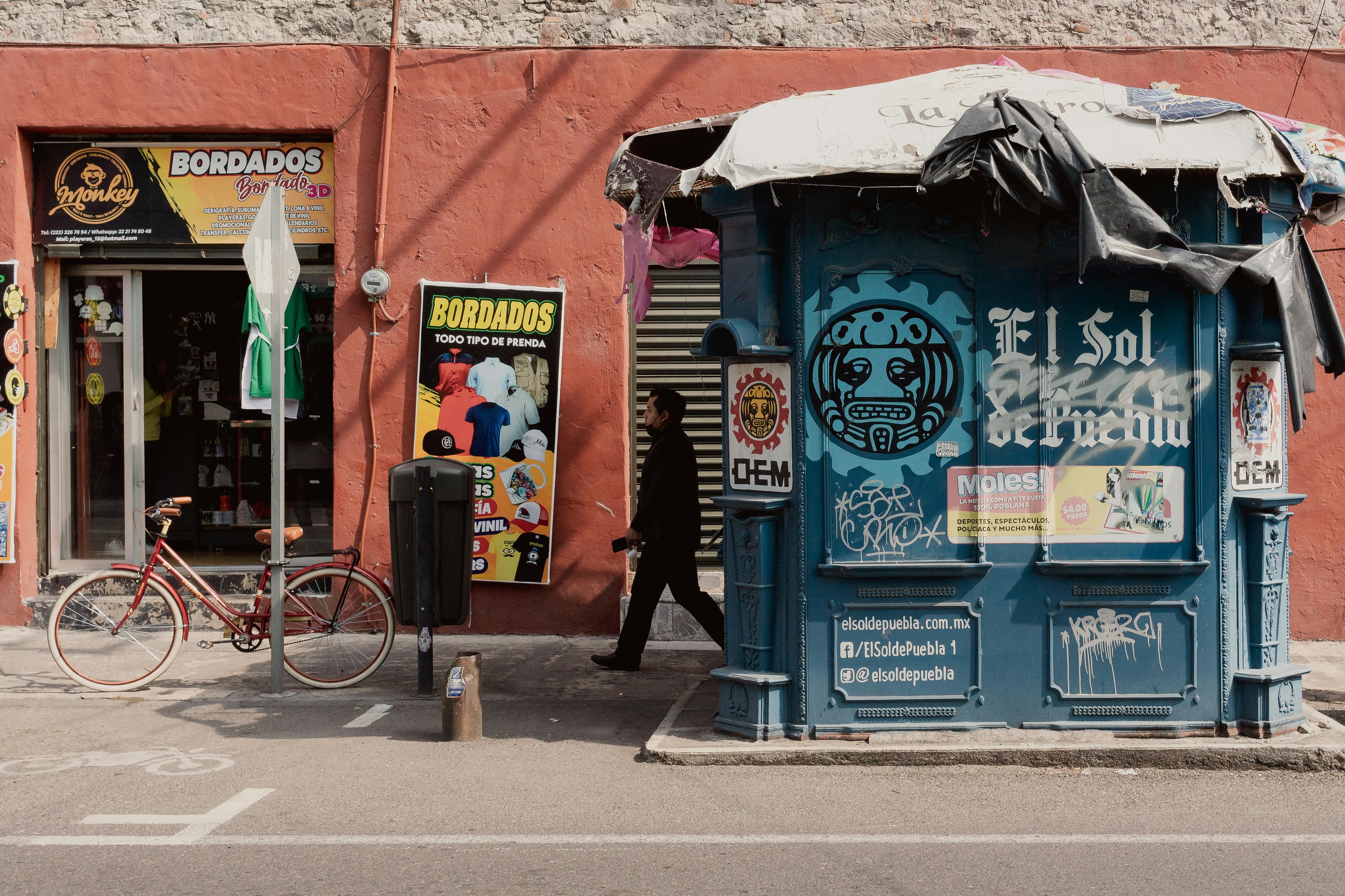 Colorful street scene in Heroica Puebla with a bike and graffiti-covered booth.