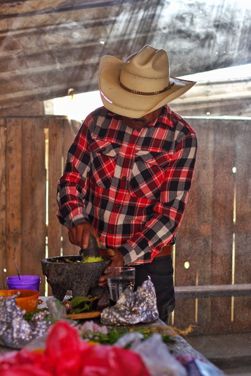 Man in Hat and Shirt Working by Table